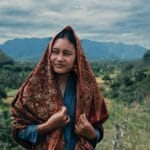 Portrait of an Indonesian woman in a headscarf, set against West Sumatra's lush landscape.